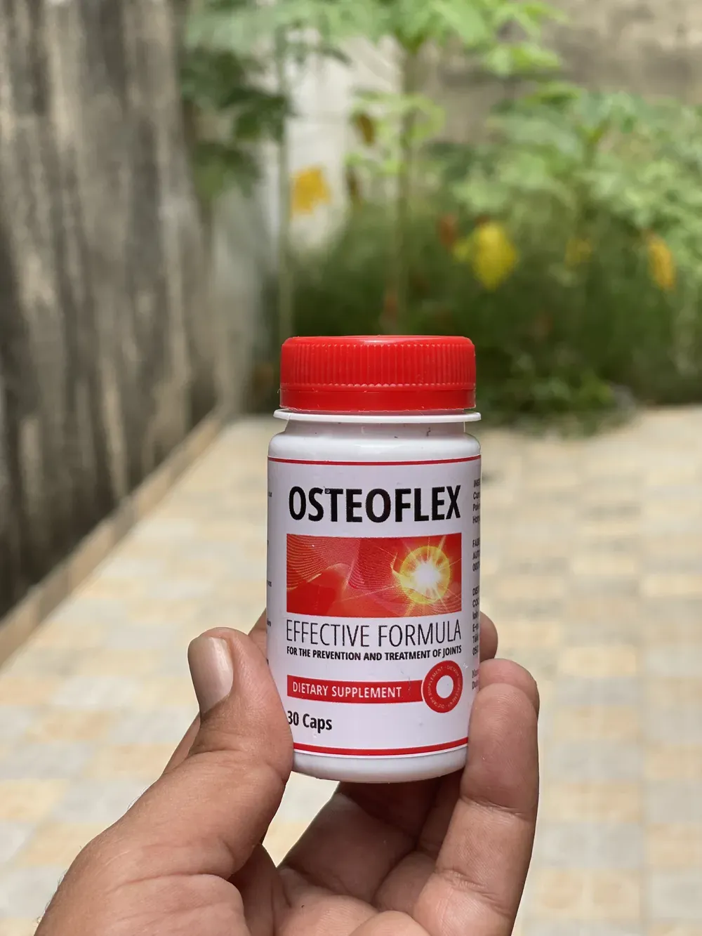 Flacon d’Osteoflex tenu à la main dans une cour à Abidjan